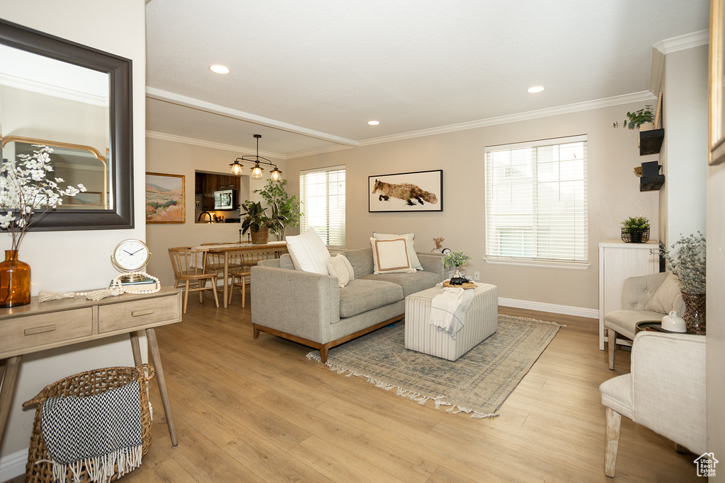 Living room featuring crown molding, light wood-type flooring, baseboards, a chandelier, and recessed lighting