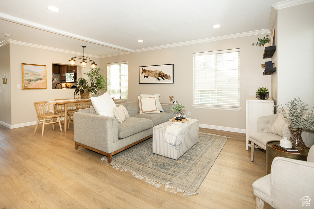 Living area with light wood-type flooring, baseboards, ornamental molding, and recessed lighting