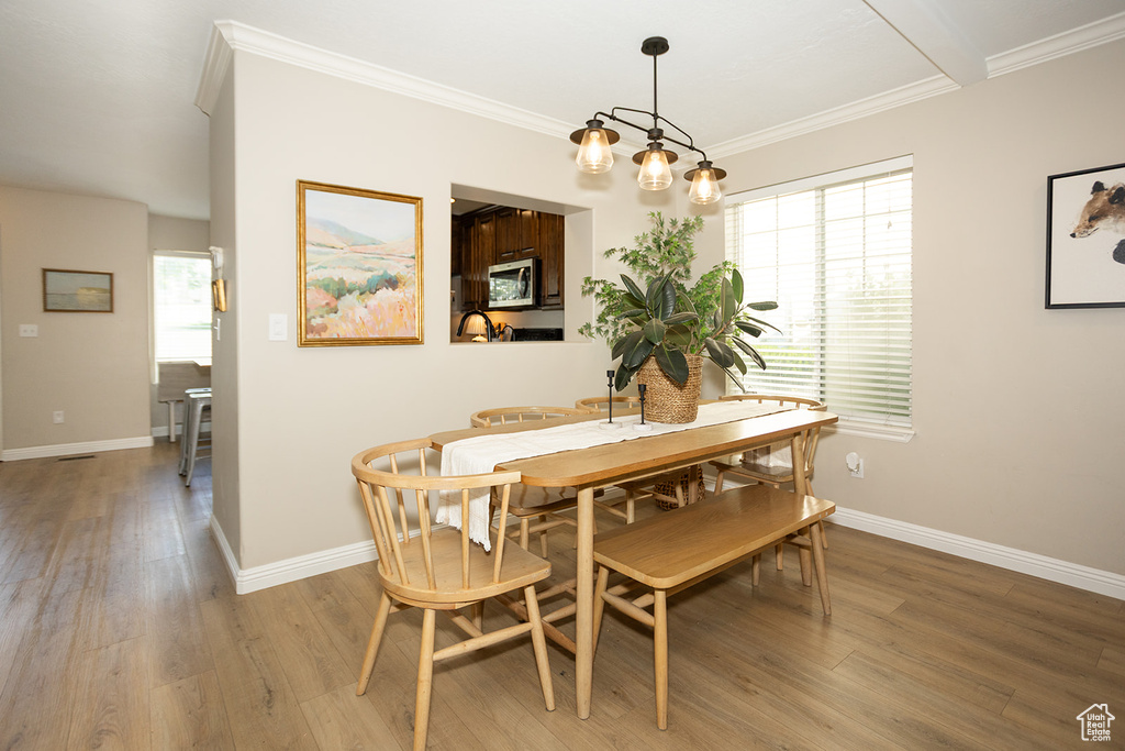 Dining area with light wood finished floors, baseboards, and ornamental molding