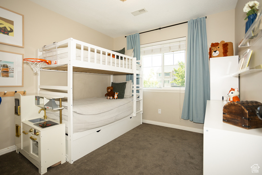 Bedroom featuring dark colored carpet and baseboards