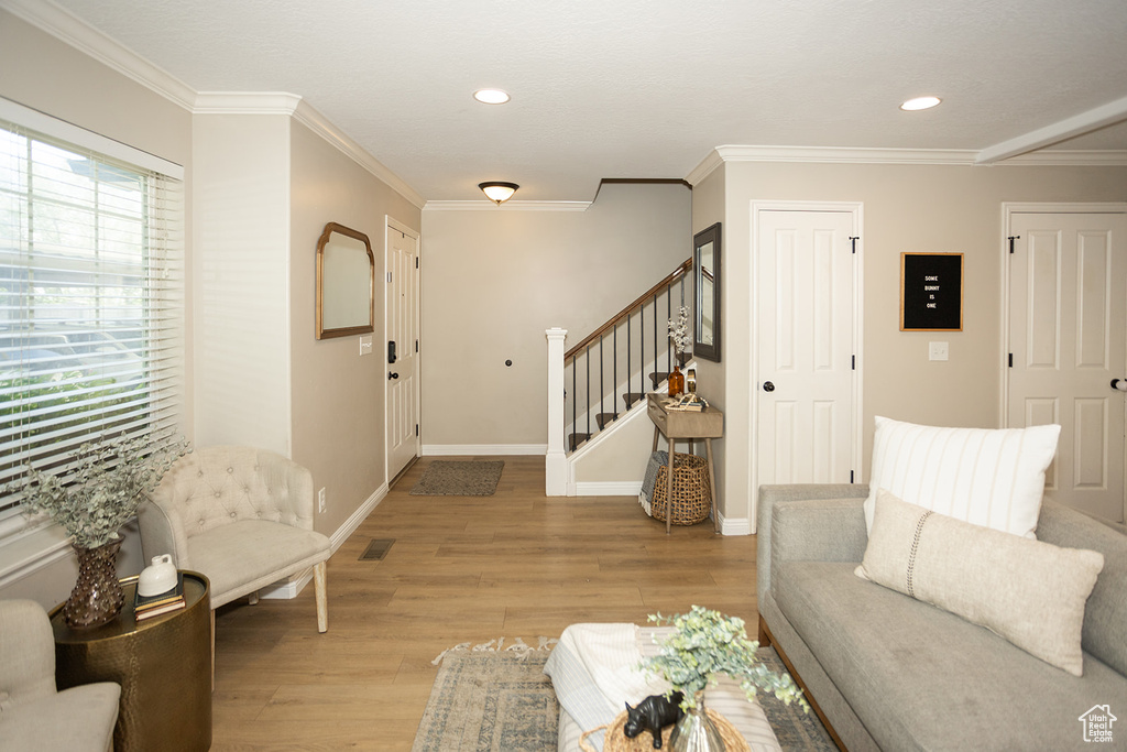 Living area with stairs, light wood-type flooring, ornamental molding, recessed lighting, and baseboards