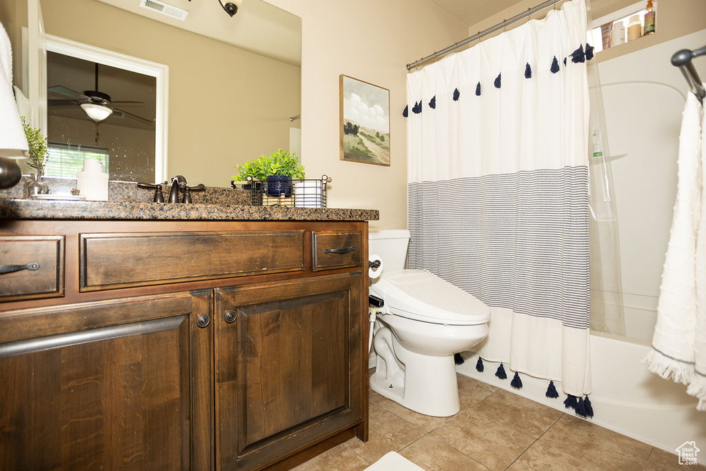 Bathroom featuring toilet, a ceiling fan, tile patterned floors, vanity, and shower / tub combo