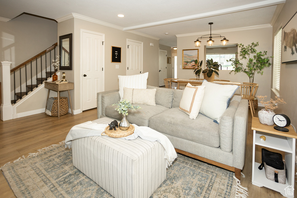 Living room with wood finished floors, stairway, ornamental molding, baseboards, and recessed lighting