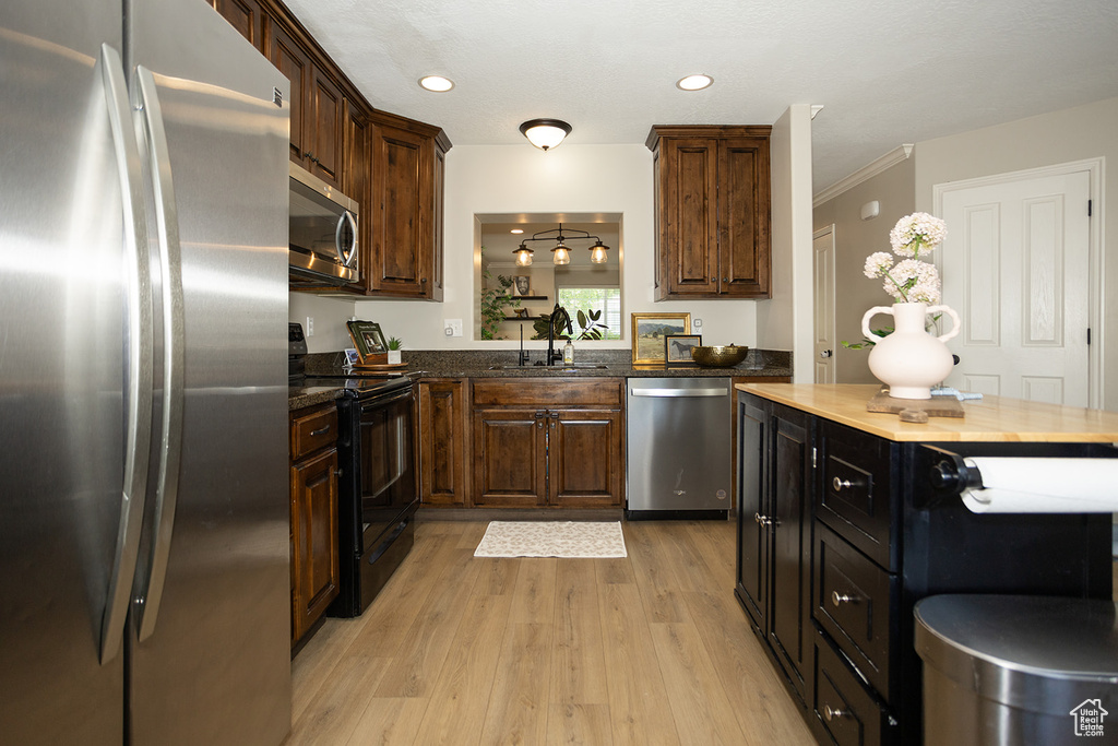 Kitchen featuring appliances with stainless steel finishes, a sink, light wood-type flooring, crown molding, and recessed lighting