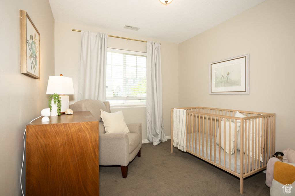 Carpeted bedroom featuring a nursery area and baseboards