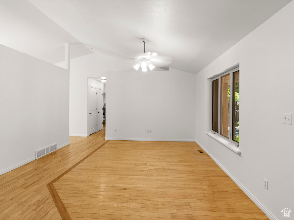 Unfurnished room with vaulted ceiling, a ceiling fan, light wood-style flooring, and baseboards