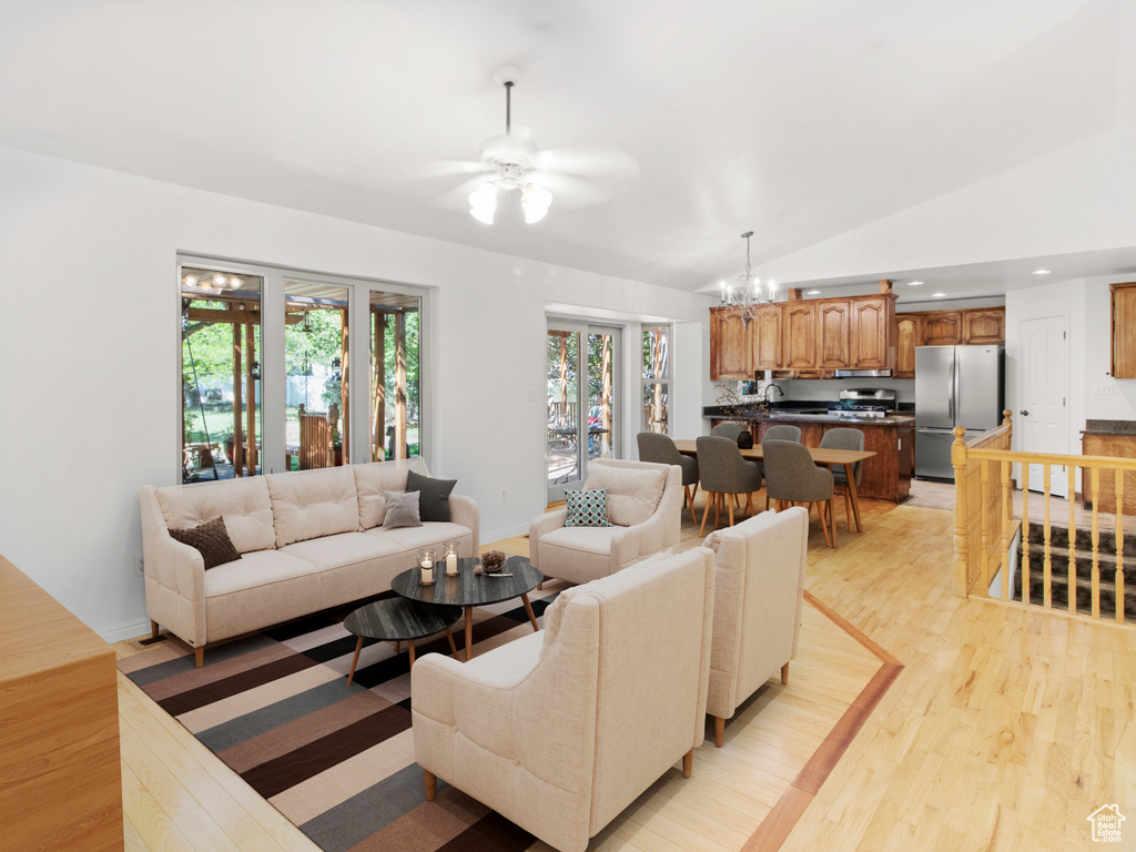 Living room with a chandelier, lofted ceiling, a ceiling fan, light wood-style floors, and recessed lighting