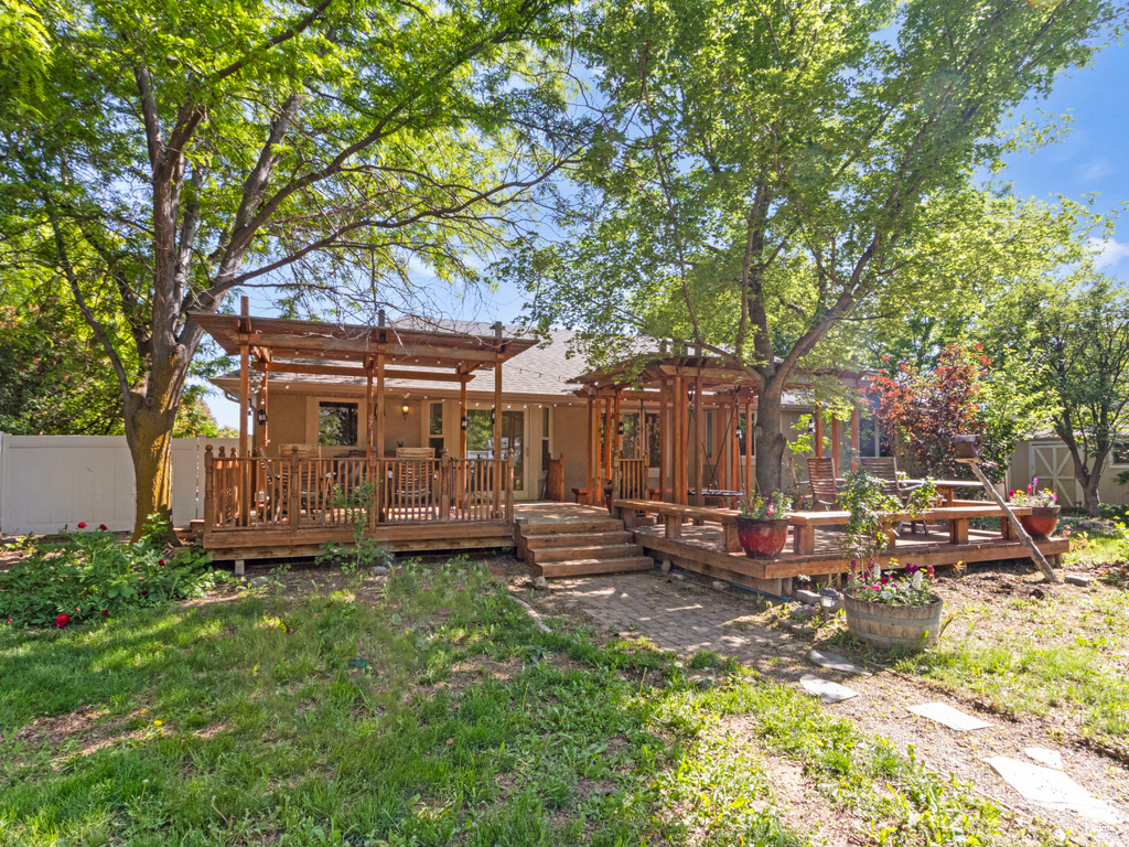 Back of property featuring a pergola and a wooden deck
