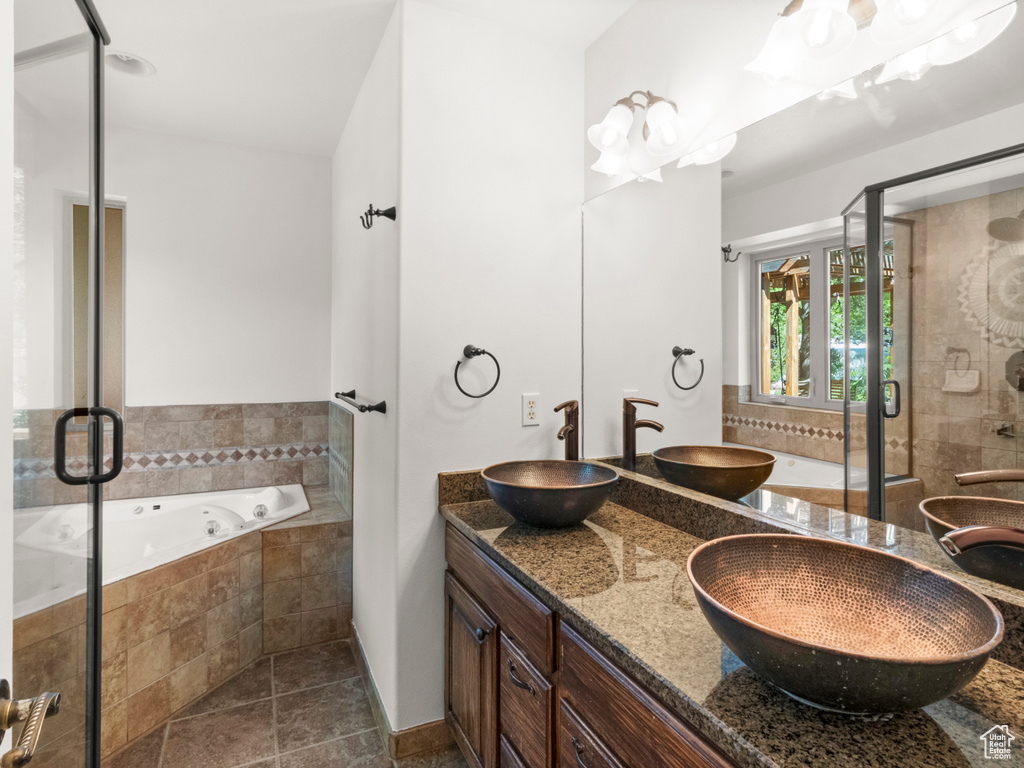 Full bath with a whirlpool tub, double vanity, and a stall shower