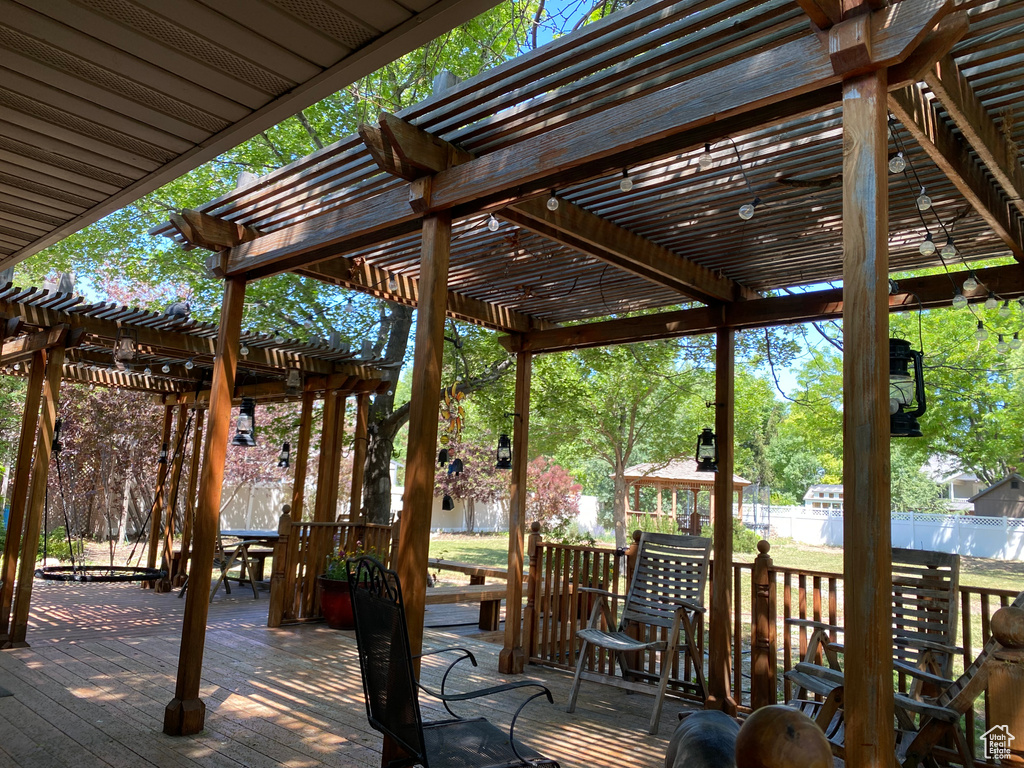 Wooden terrace with a pergola, a fenced backyard, and outdoor dining space