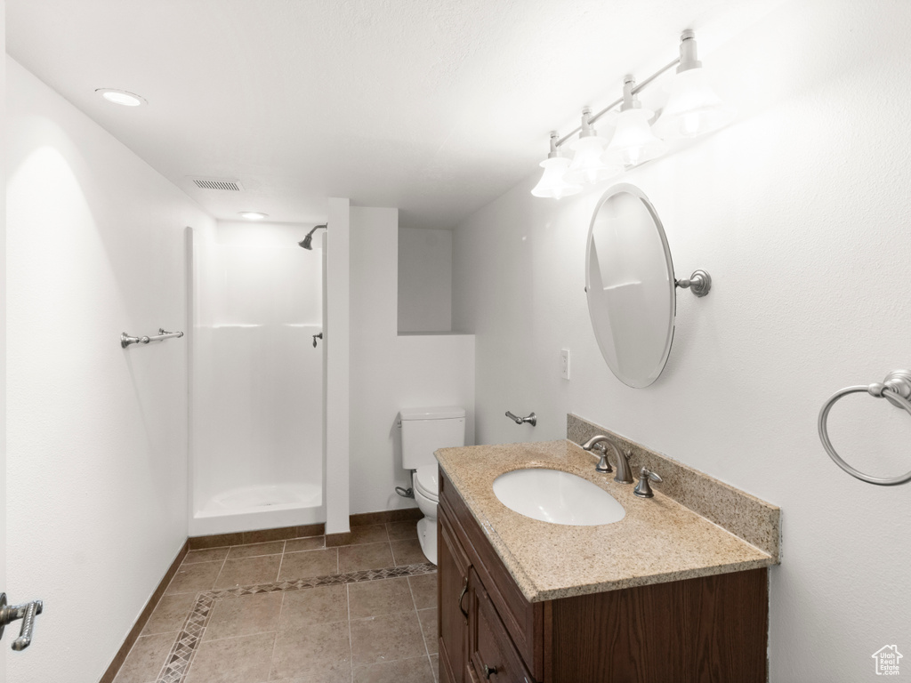 Full bathroom with vanity, toilet, a shower, baseboards, and tile patterned floors