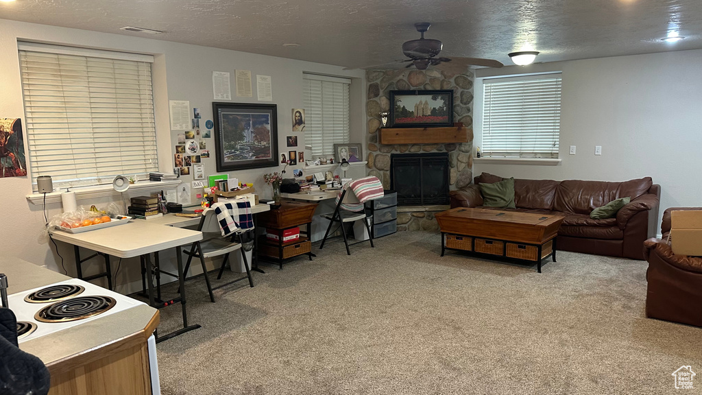 Carpeted living room with a fireplace, ceiling fan, and a textured ceiling