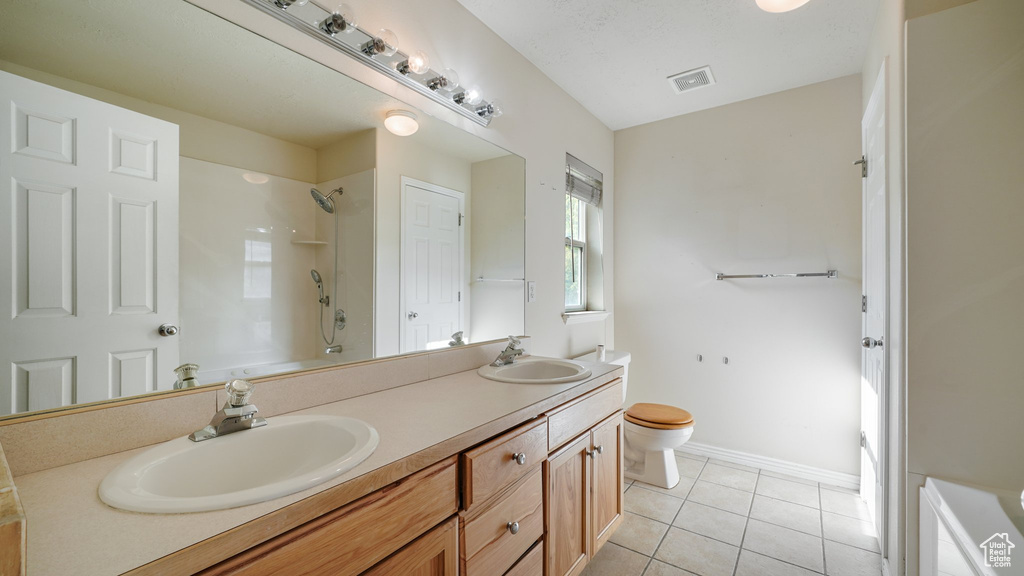 Bathroom with double vanity, toilet, tile patterned floors, a shower, and baseboards