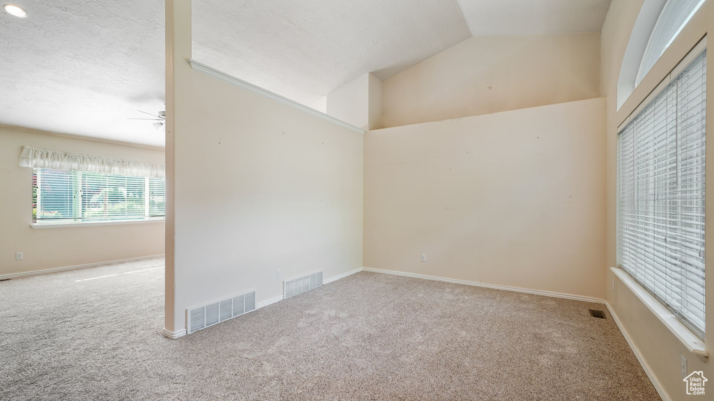 Empty room with carpet, ceiling fan, vaulted ceiling, and baseboards