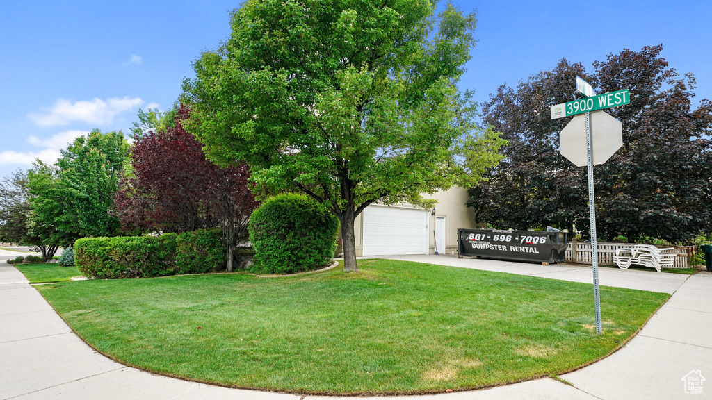 View of property exterior with a garage, a yard, and driveway