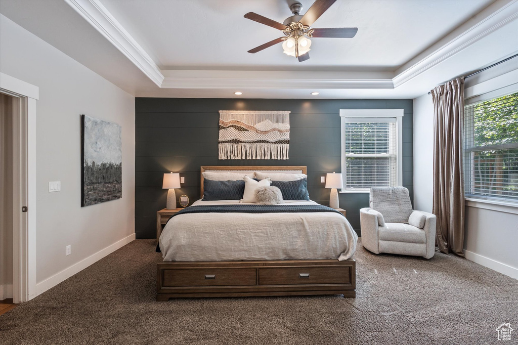 Carpeted bedroom with a tray ceiling, baseboards, and ceiling fan