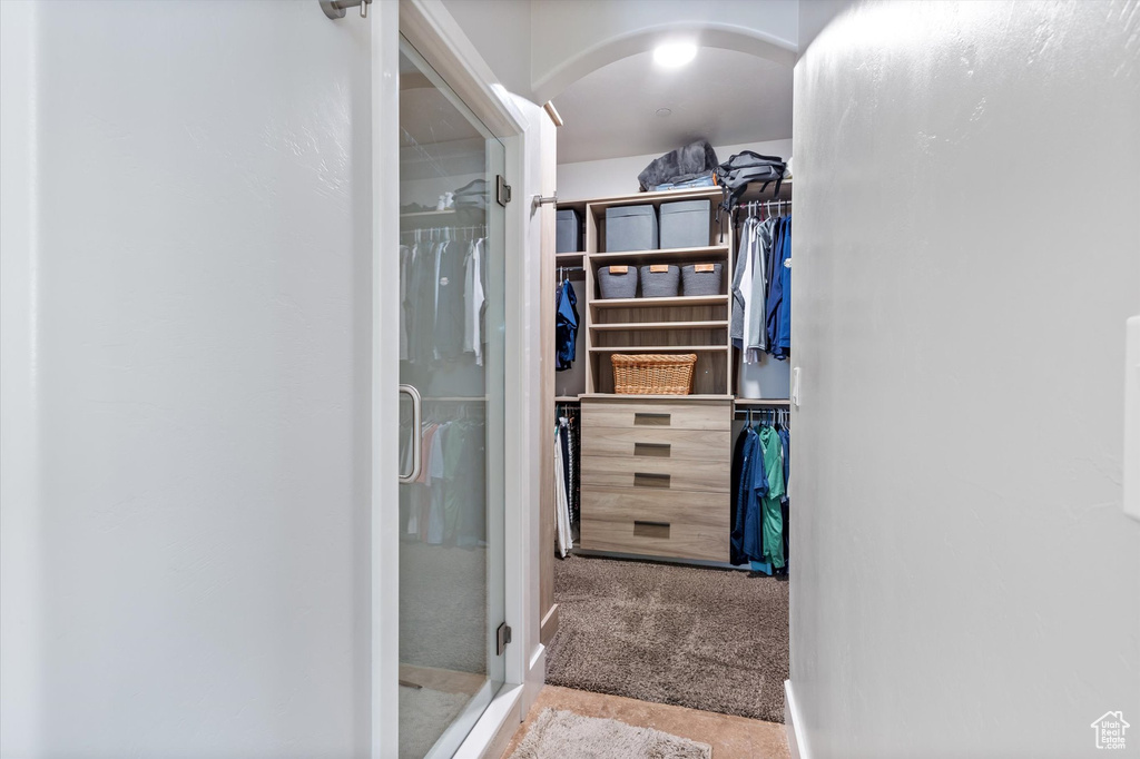 Walk in closet with arched walkways and carpet floors