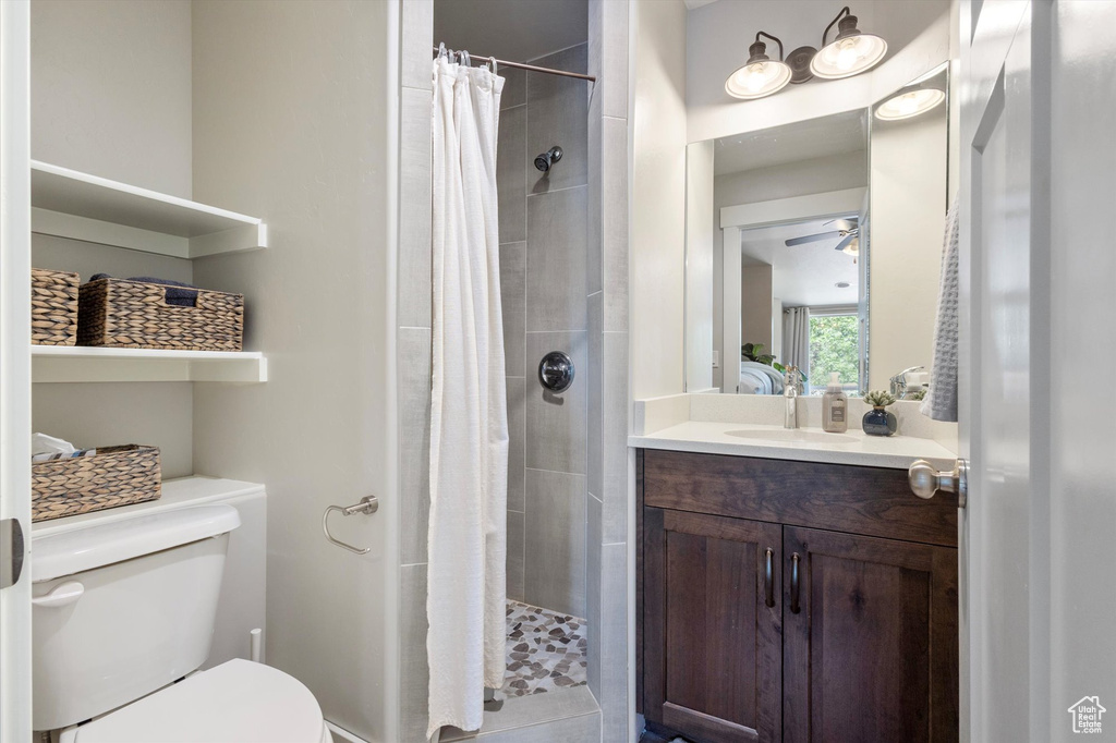 Full bath featuring toilet, a stall shower, a ceiling fan, and vanity