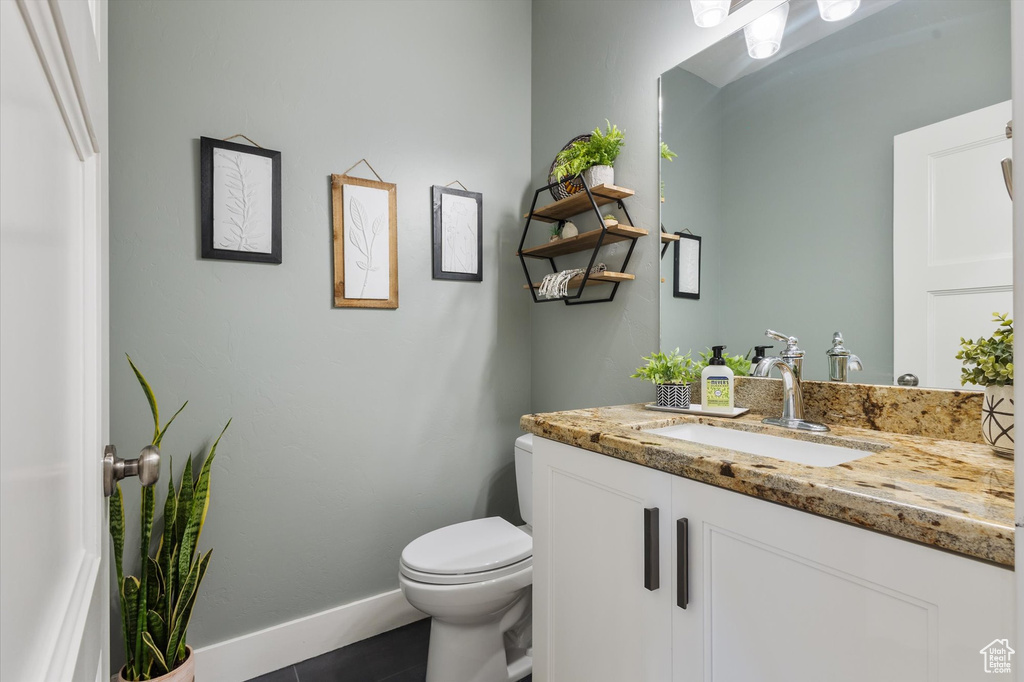 Bathroom featuring toilet, baseboards, and vanity