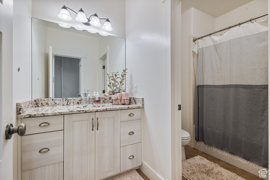 Bathroom with toilet, vanity, and curtained shower