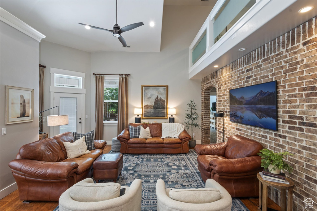 Living area featuring ceiling fan, wood finished floors, baseboards, brick wall, and recessed lighting