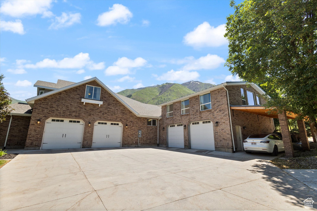 View of front facade with concrete driveway, a mountain view, brick siding, and an attached garage
