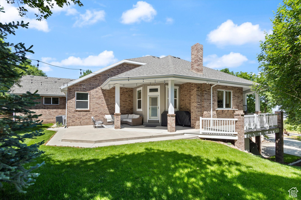 Back of house with a lawn, central AC, an outdoor hangout area, and a chimney