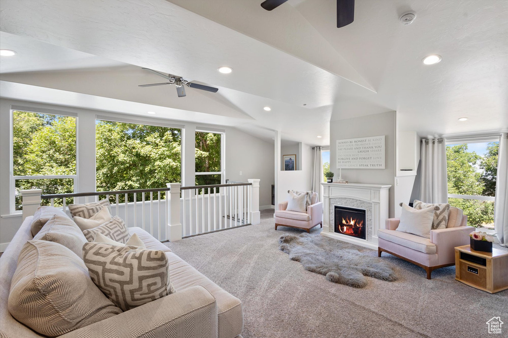 Carpeted living area with a ceiling fan, recessed lighting, vaulted ceiling, a lit fireplace, and baseboards