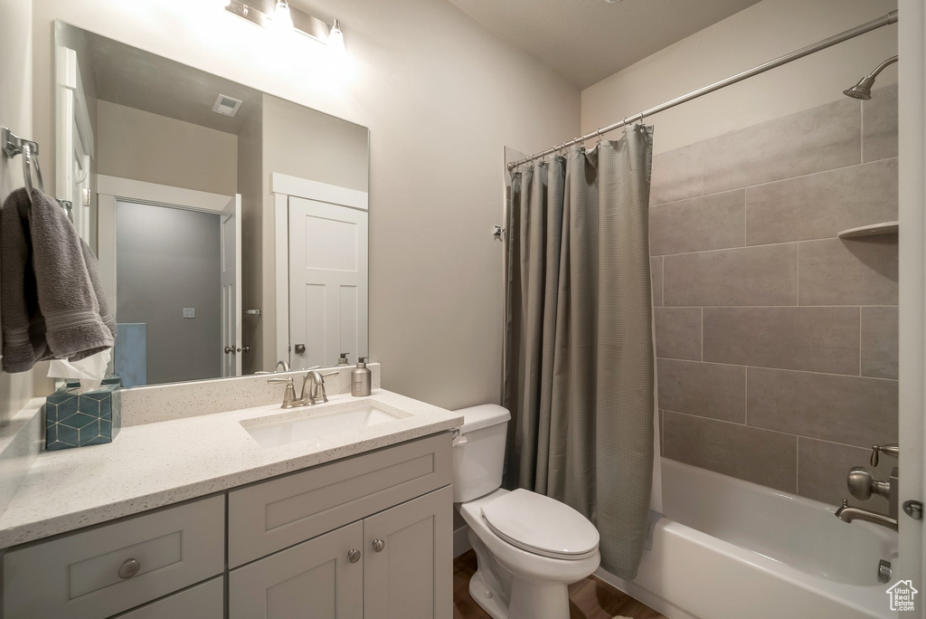 Bathroom with toilet, vanity, and shower / bathtub combination with curtain