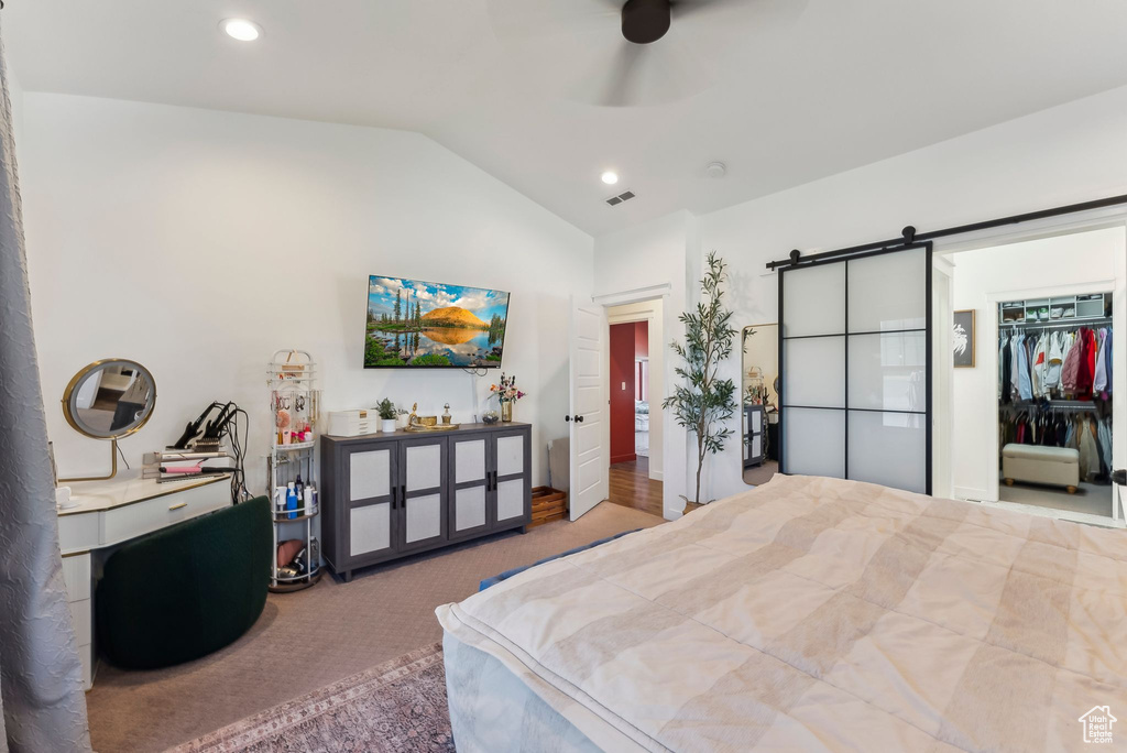 Carpeted bedroom featuring vaulted ceiling, a barn door, recessed lighting, a walk in closet, and a closet