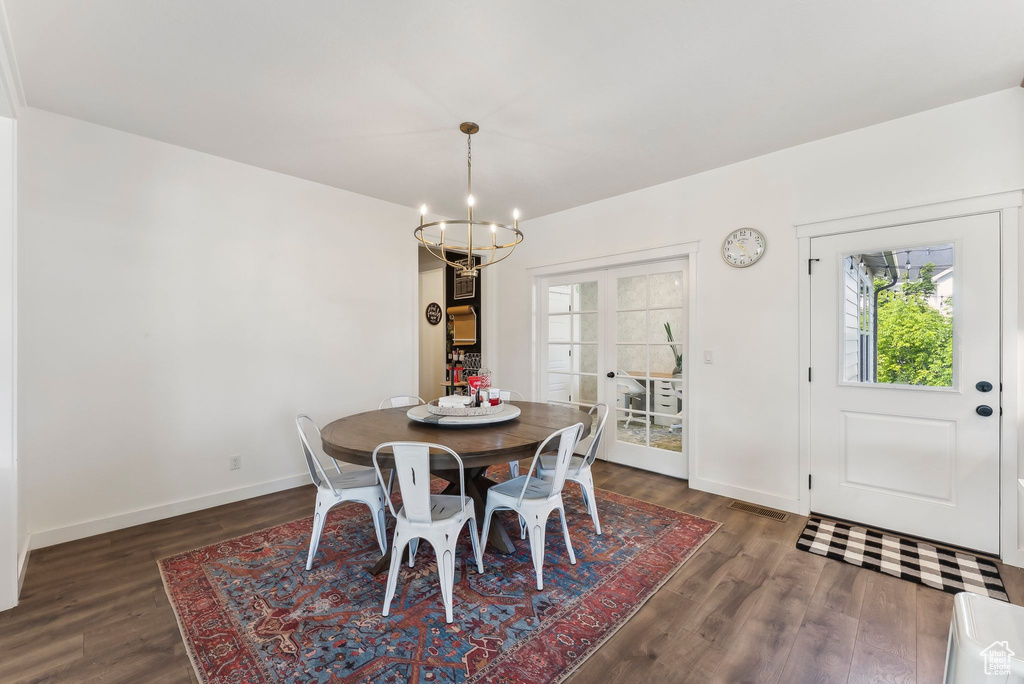 Dining space with a chandelier, dark wood-style flooring, plenty of natural light, and baseboards