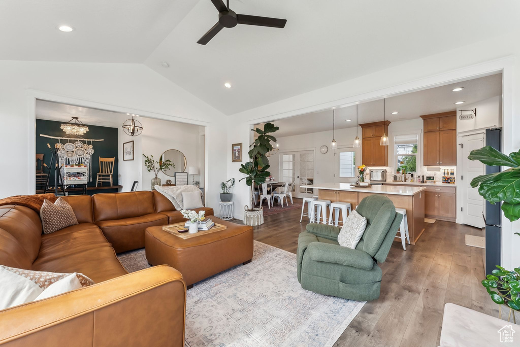Living area featuring lofted ceiling, ceiling fan, a chandelier, wood finished floors, and recessed lighting