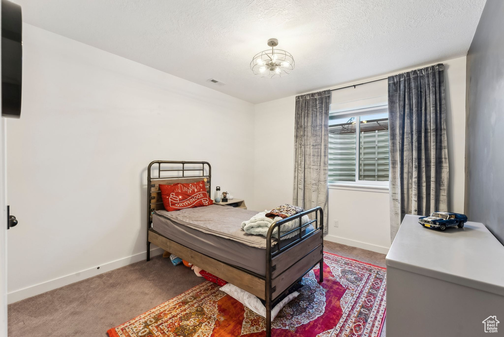 Carpeted bedroom with baseboards and a textured ceiling