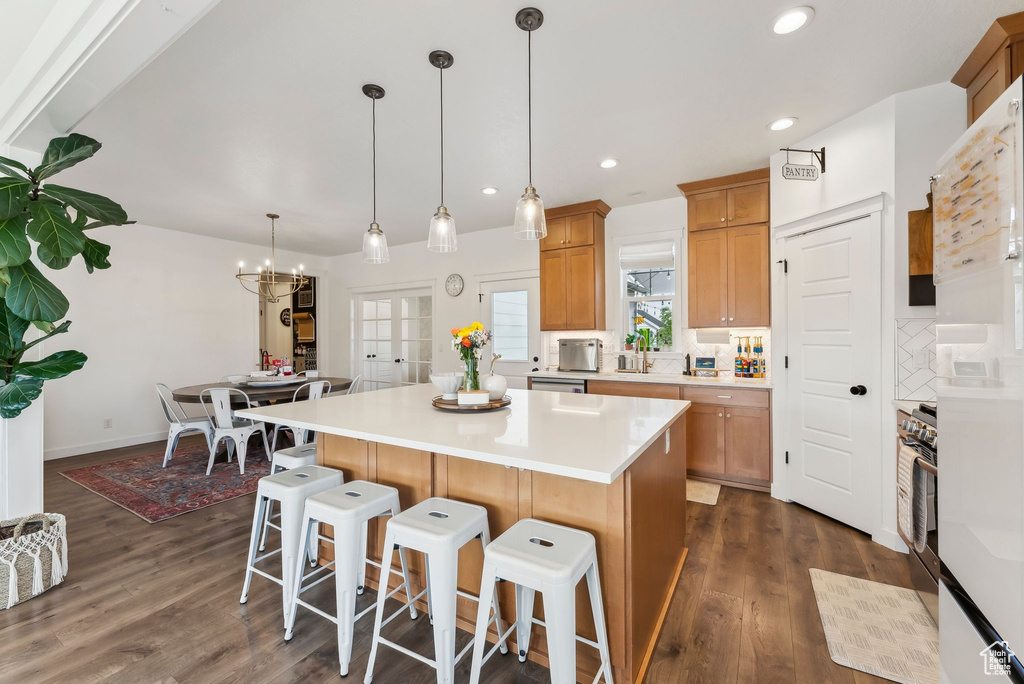 Kitchen featuring a kitchen breakfast bar, dark wood finished floors, a kitchen island, light countertops, and a chandelier