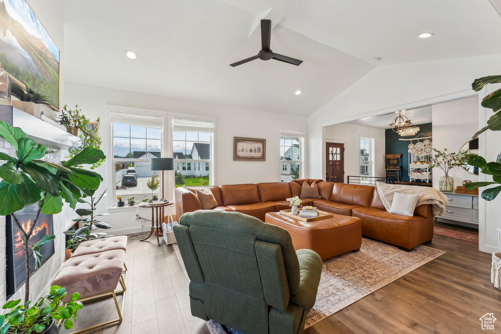 Living room featuring lofted ceiling, ceiling fan, a chandelier, wood finished floors, and recessed lighting