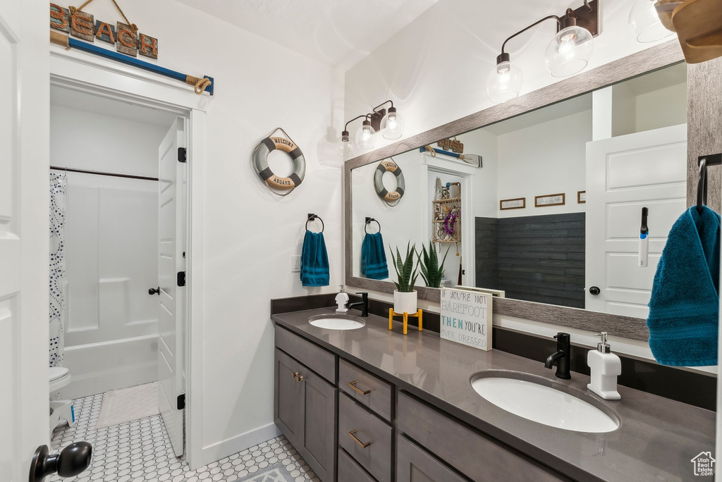 Full bathroom featuring double vanity, baseboards, and shower / tub combo