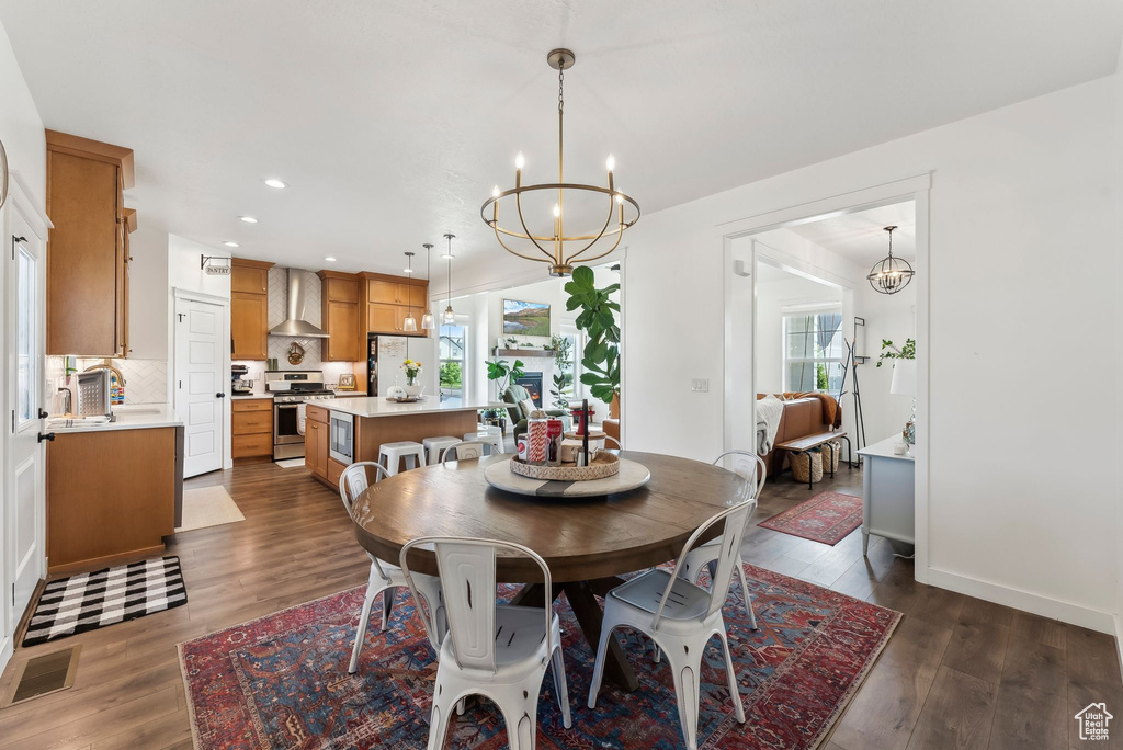 Dining room with a chandelier, plenty of natural light, recessed lighting, and dark wood-style flooring