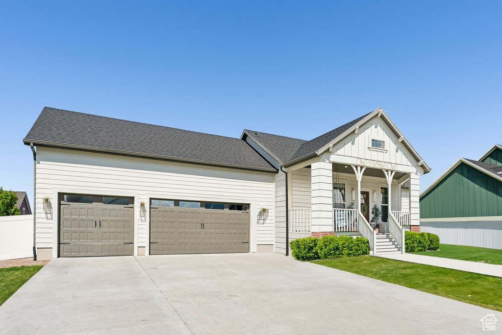 View of front of home with covered porch, driveway, board and batten siding, and a garage