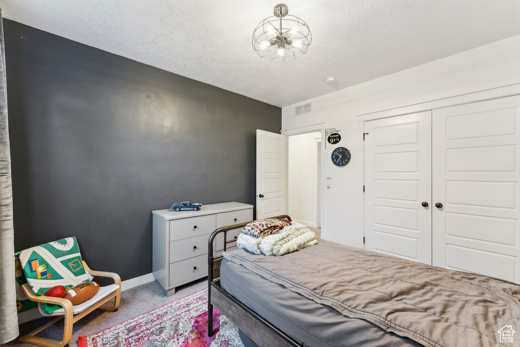 Carpeted bedroom featuring a closet, baseboards, and a textured ceiling