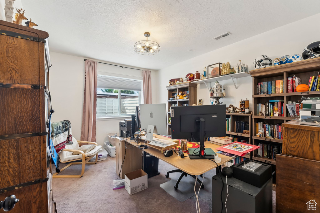 Carpeted home office featuring a chandelier and a textured ceiling