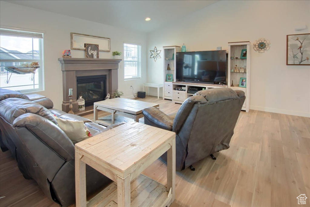Living room with light wood-type flooring, baseboards, a glass covered fireplace, and recessed lighting