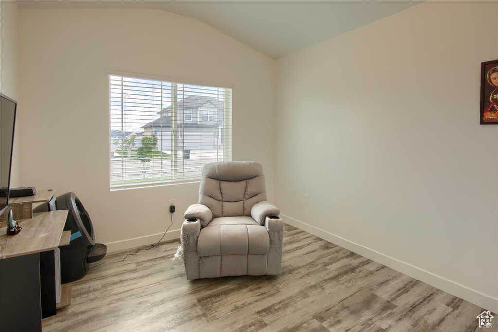 Living area featuring light wood-style floors, baseboards, and lofted ceiling