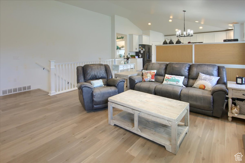Living area featuring a chandelier, lofted ceiling, light wood-type flooring, and recessed lighting