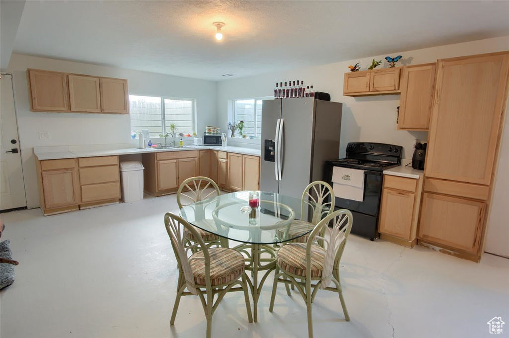 Kitchen with light brown cabinets, appliances with stainless steel finishes, a sink, and light countertops