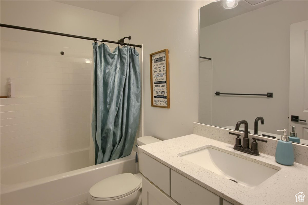 Full bathroom with toilet, shower / bathtub combination with curtain, and vanity