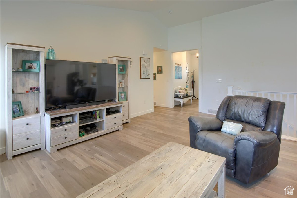 Living area with light wood-type flooring, high vaulted ceiling, and baseboards