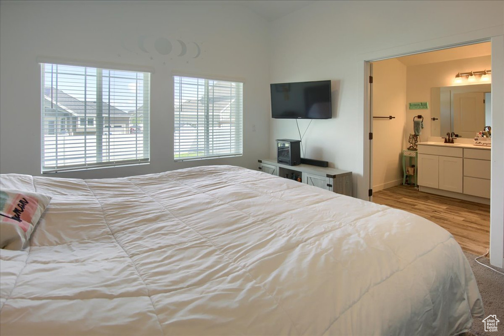 Bedroom featuring a sink, wood finished floors, baseboards, and ensuite bathroom