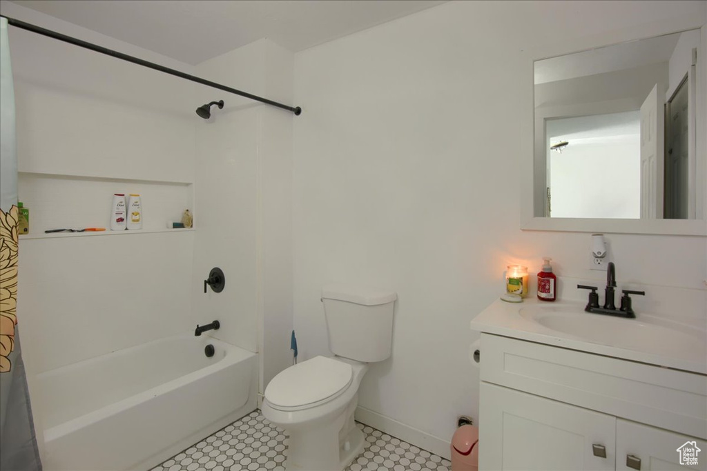 Full bathroom featuring toilet, vanity, baseboards, and shower / bath combination