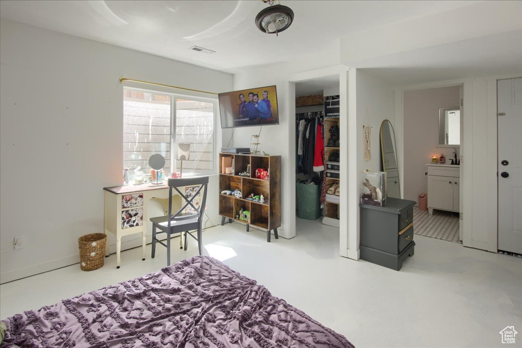 Bedroom featuring a closet, a walk in closet, ensuite bath, and concrete floors
