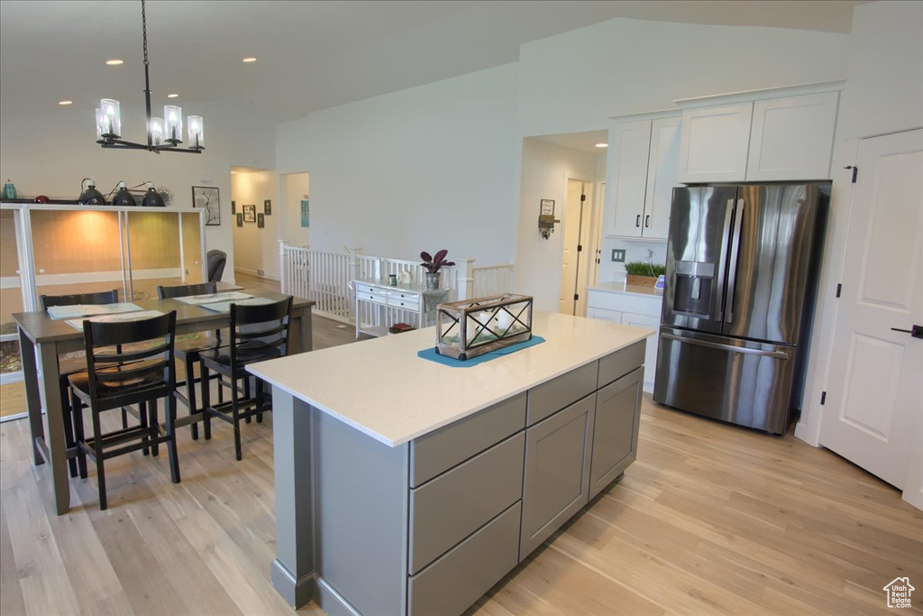 Kitchen featuring stainless steel fridge with ice dispenser, light wood-style floors, a kitchen island, light countertops, and gray cabinetry